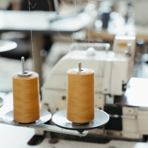 Detailed view of a sewing machine with spools of thread in a workshop setting.